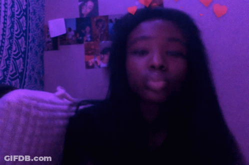 A Girl Is Smoking A Cigarette In Front Of A Purple Wall GIF