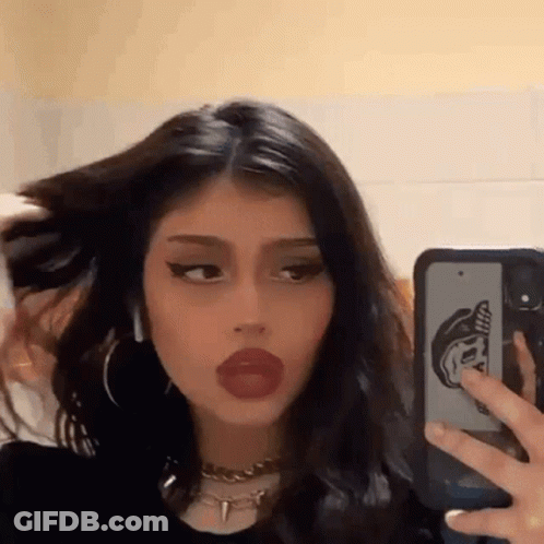 A Girl Is Taking A Picture Of Herself In The Mirror With Her Phone . GIF