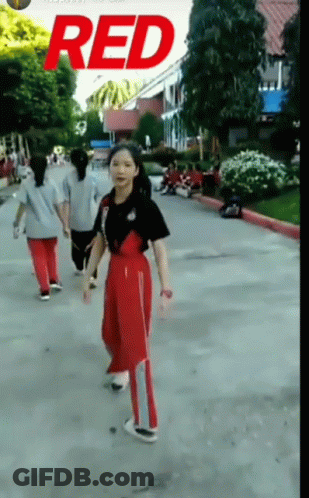 A Girl Is Walking Down A Street With The Word Red On The Bottom GIF