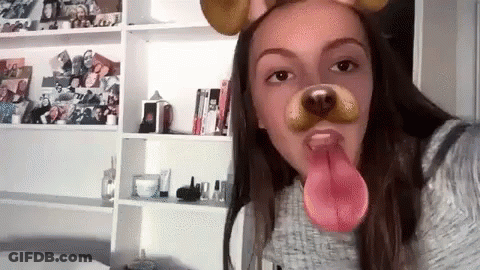 A Girl Is Wearing A Dog Mask With Her Tongue Out . GIF