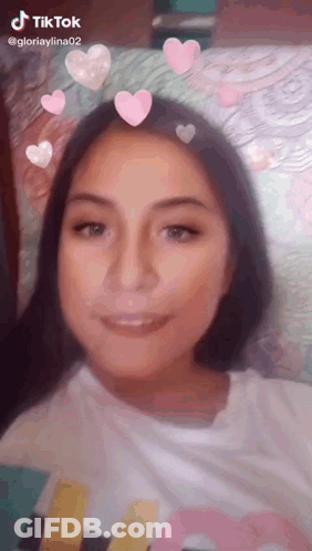 A Girl Is Wearing A Tiktok Filter With Pink Hearts On Her Hair . GIF