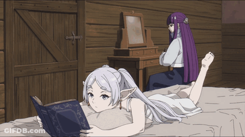 A Girl Laying On A Bed Reading A Book While Another Girl Sits In The Background GIF