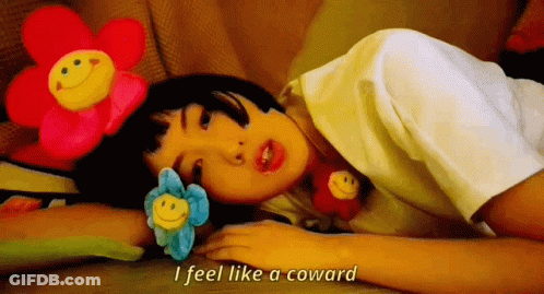 A Girl Laying On The Floor With Stuffed Flowers On Her Head And The Words I Feel Like A Coward GIF