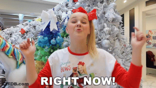 A Girl Standing In Front Of A Christmas Tree With The Words Right Now Written Below Her GIF