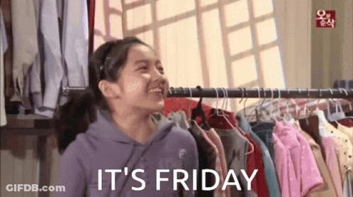 A Girl Standing In Front Of A Rack Of Clothes With The Words It 'S Friday Written Below Her GIF