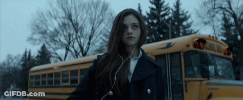 A Girl Standing In Front Of A School Bus GIF