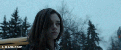 A Girl Standing In Front Of A Yellow School Bus GIF
