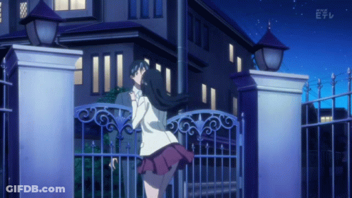 A Girl Stands In Front Of A Building With A Fence And A Sign That Says Nhk E GIF