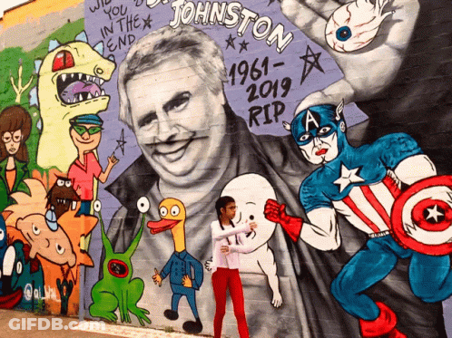 A Girl Stands In Front Of A Mural Of Johnston GIF