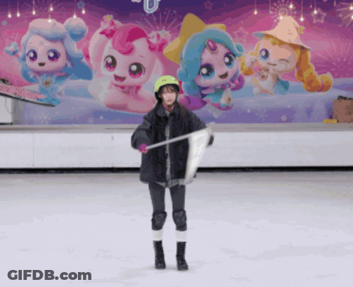 A Girl Stands On A Ice Rink Holding A Flag In Front Of A Wall With Cartoon Characters On It GIF