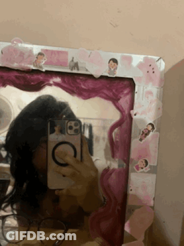 A Girl Taking A Picture Of Herself In A Mirror With A Pink Frame GIF