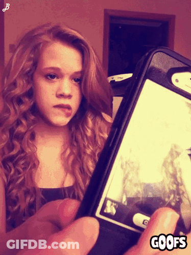 A Girl Taking A Picture Of Herself With A Phone That Says Goofs On The Bottom GIF