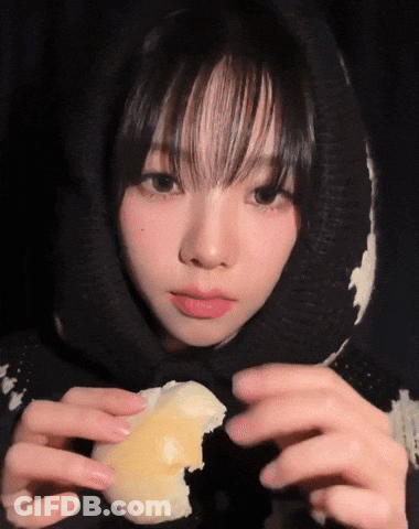 A Girl Wearing A Black And White Sweater Is Holding A Piece Of Cheese In Her Hands GIF