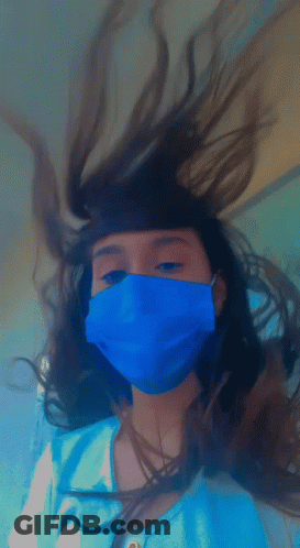 A Girl Wearing A Blue Mask Has Her Hair Blowing In The Wind GIF