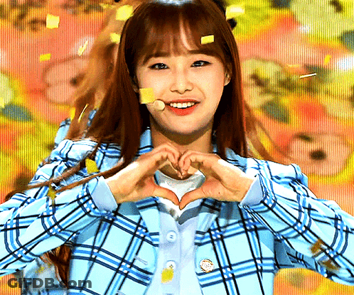 A Girl Wearing A Blue Plaid Jacket Making A Heart Shape With Her Hands GIF