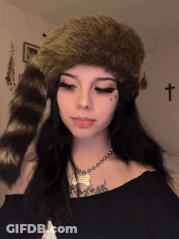A Girl Wearing A Fur Hat And A Necklace With A Dog Tag That Says ' I Love You ' On It GIF