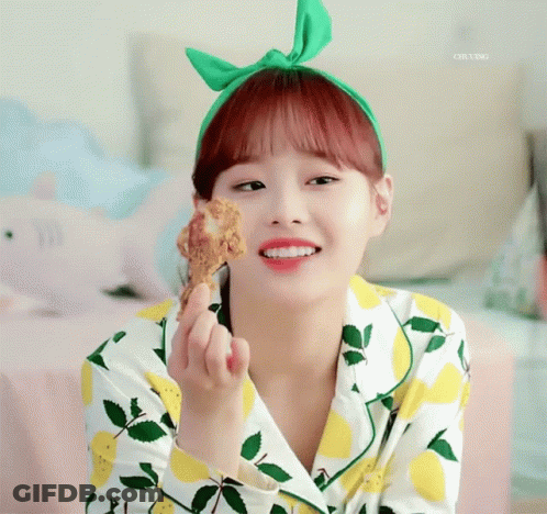 A Girl Wearing A Green Headband Is Holding A Piece Of Fried Chicken GIF