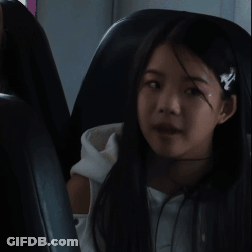 A Girl Wearing A Headband With The Letter N On It Sits In A Chair GIF