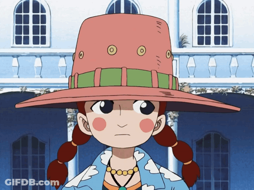 A Girl Wearing A Pink Hat With Circles On It Stands In Front Of A Building GIF