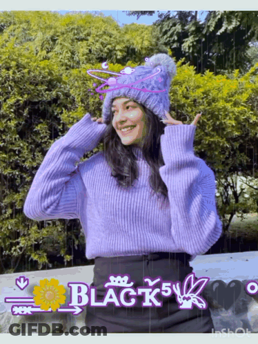 A Girl Wearing A Purple Sweater And A Knitted Hat With The Word Black On It GIF