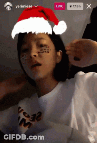 A Girl Wearing A Santa Hat And A T-Shirt That Says ' Merry Christmas ' On It GIF