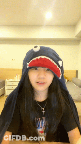 A Girl Wearing A Shark Hat And A Shirt That Says Devil On It GIF