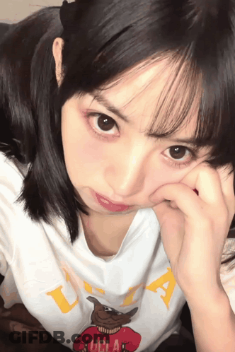 A Girl Wearing A Ucla T-Shirt Covering Her Face With Her Hand GIF