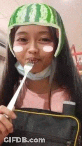 A Girl Wearing A Watermelon Hat Is Eating With A Fork . GIF