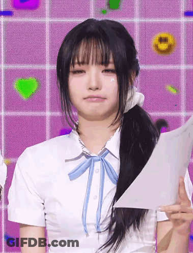 A Girl Wearing A White Shirt With A Blue Bow Tie Holds A Piece Of Paper GIF
