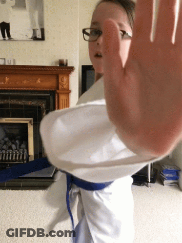 A Girl Wearing Glasses And A Blue Belt Is Making A Stop Gesture GIF
