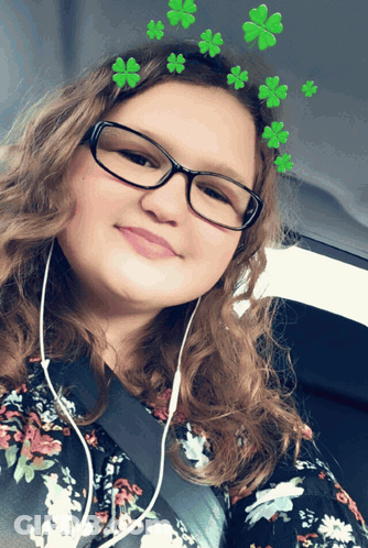 A Girl Wearing Glasses And A Floral Shirt Has Green Clovers On Her Head GIF