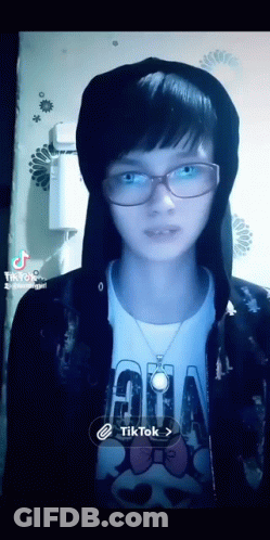 A Girl Wearing Glasses And A Hoodie Has A Tiktok Icon On The Bottom Right GIF