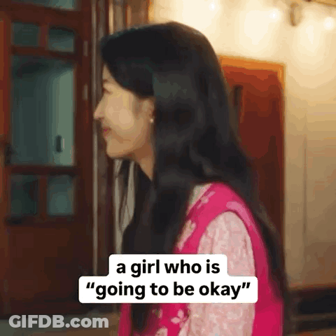 A Girl Who Is Going To Be Okay Is Standing In Front Of A Door And Smiling . GIF