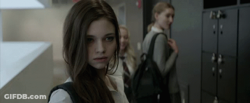 A Girl With A Backpack Is Standing In A Hallway GIF