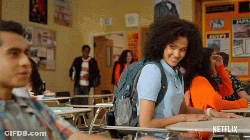 A Girl With A Backpack Sits At A Desk In A Classroom With A Sign That Says Egypt On It GIF