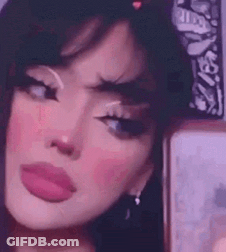 A Girl With A Bandana On Her Head Is Taking A Selfie In Front Of A Mirror . GIF