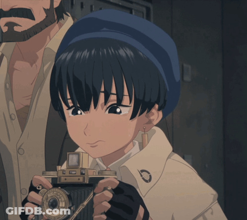 A Girl With A Blue Hat Is Holding A Small Camera GIF