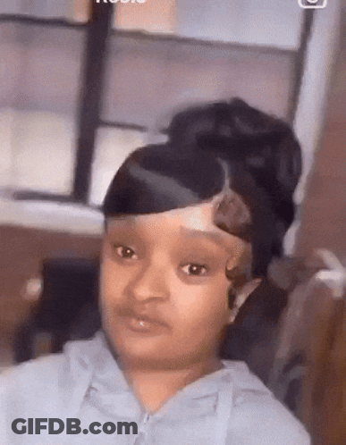 A Girl With A Bun On Her Head Is Looking At The Camera . GIF