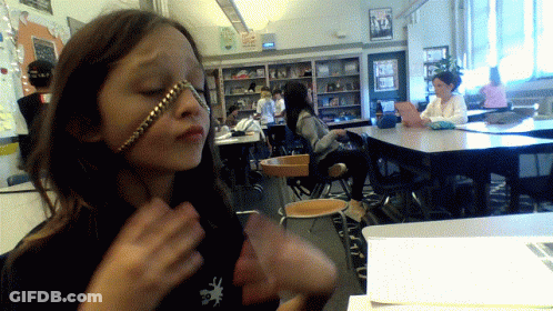 A Girl With A Chain Around Her Face Is In A Classroom With Other Students GIF