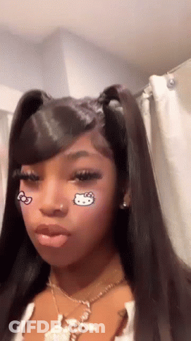 A Girl With A Hello Kitty Tattoo On Her Face Is Wearing A Necklace And Earrings . GIF