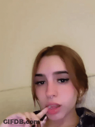 A Girl With A Piercing In Her Nose Is Making A Funny Face With Her Fingers . GIF