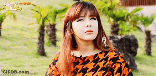 A Girl With A Question Mark On Her Forehead Is Standing In A Field With Palm Trees . GIF