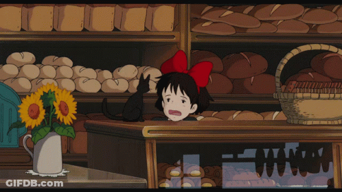 A Girl With A Red Bow On Her Head Stands In Front Of A Bakery GIF