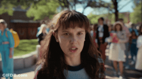 A Girl With A Serious Look On Her Face Is Standing In Front Of A Crowd Of People GIF