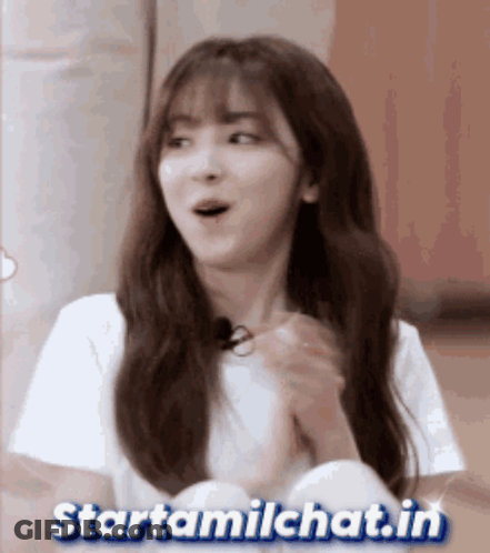 A Girl With A Surprised Look On Her Face Is Sitting In Front Of A Sign That Says Startamilchat.in GIF