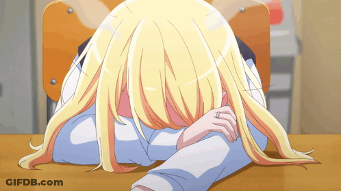 A Girl With Blonde Hair Is Laying On A Desk With Her Head On Her Arm GIF