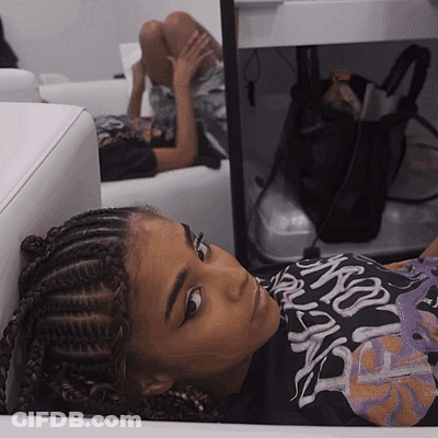 A Girl With Braids Is Laying On A Couch Wearing A Shirt That Says ' Nsfw ' GIF