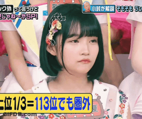 A Girl With Flowers In Her Hair Is Sitting In Front Of A Sign That Says ' 113 ' On It GIF