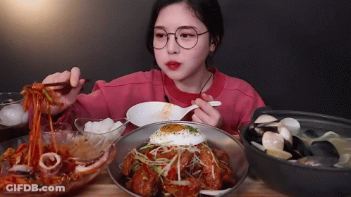 A Girl With Glasses Is Eating Noodles With Chopsticks GIF