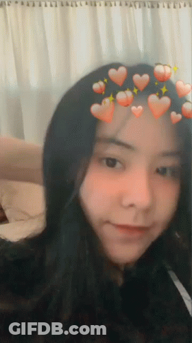 A Girl With Hearts On Her Head Is Smiling GIF